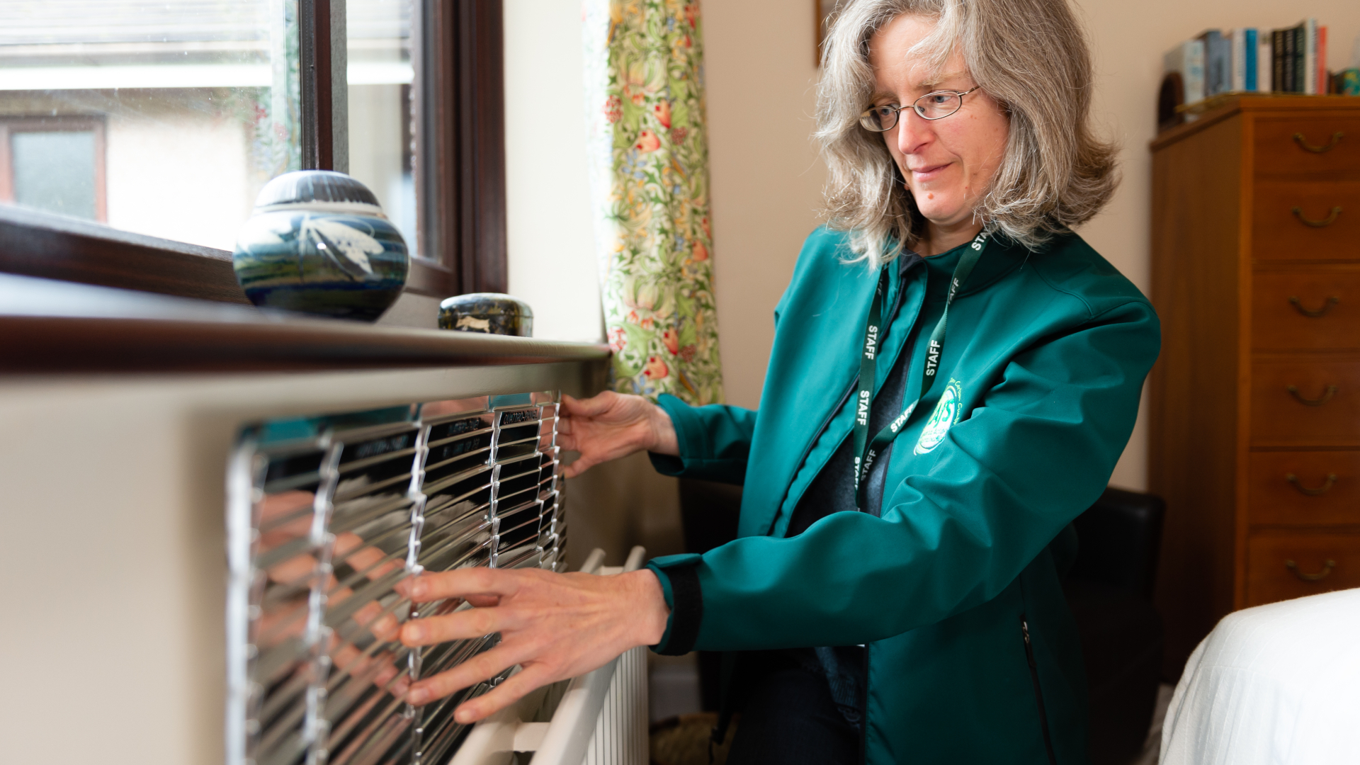 Tina from CAfS fits a radiator reflector during a Cold to Cosy Homes Cumbria visit