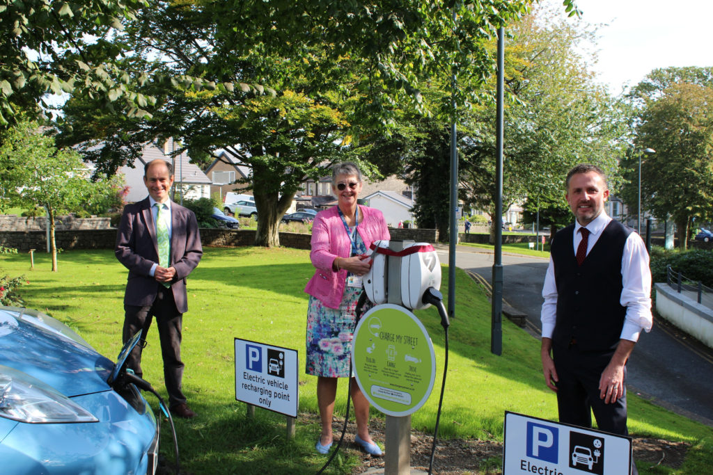 Three people standing around a chargepoint while one of them cuts a ribbon