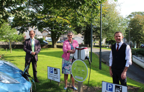 Three people standing around a chargepoint while one of them cuts a ribbon