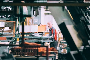 A worker in a factory setting viewed from a distance