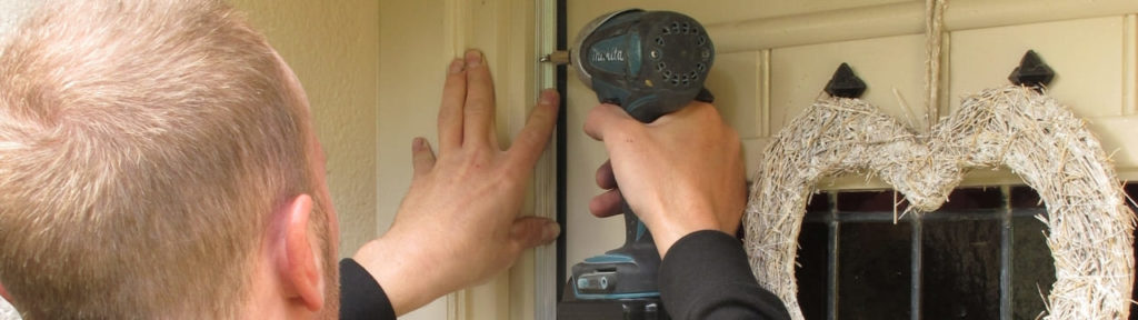 An installer using a drill to install a door draughtproofing seal