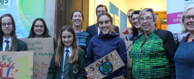 School pupils holding climate signs with Cumbria councillor