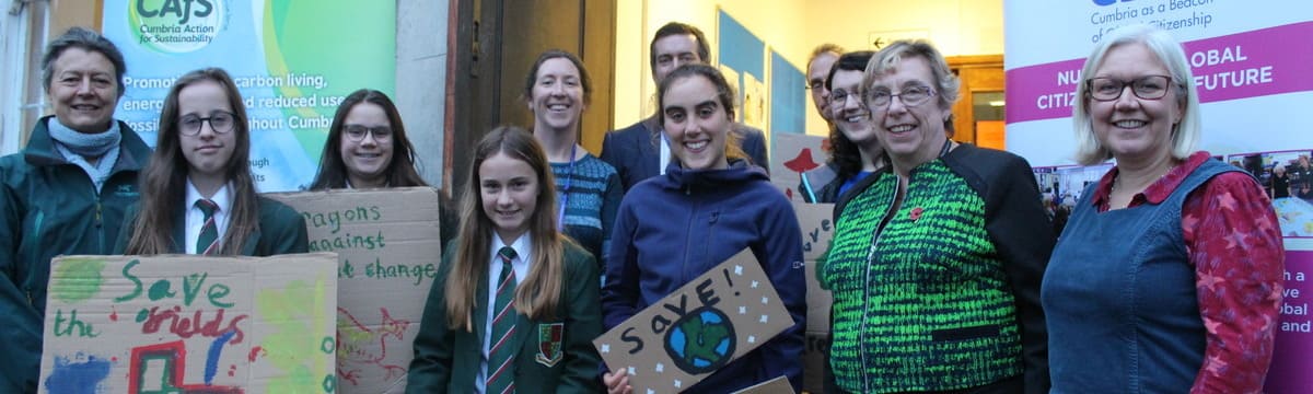 School pupils holding climate signs with Cumbria councillor