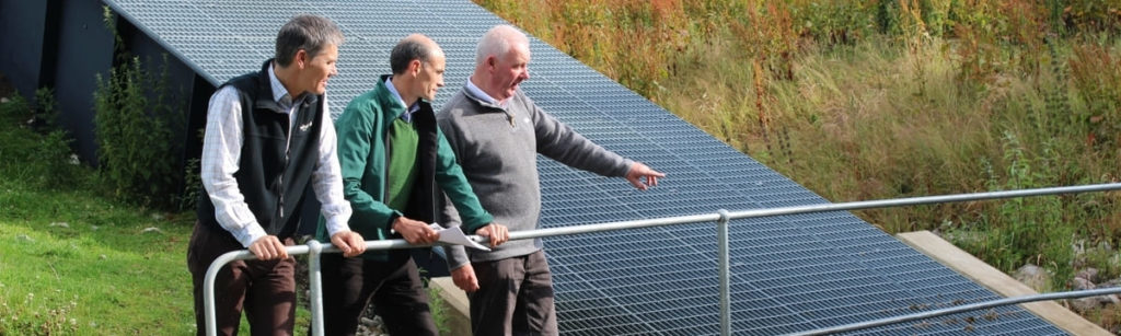 Three men standing near a hydro power station