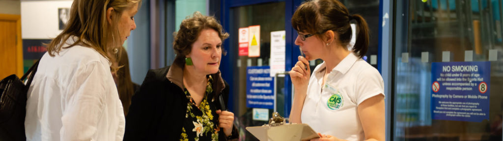 A member of the CAfS team helps members of the public at an event sign-in desk.