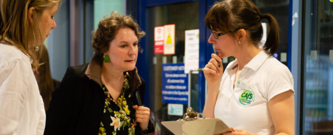 A member of the CAfS team helps members of the public at an event sign-in desk.