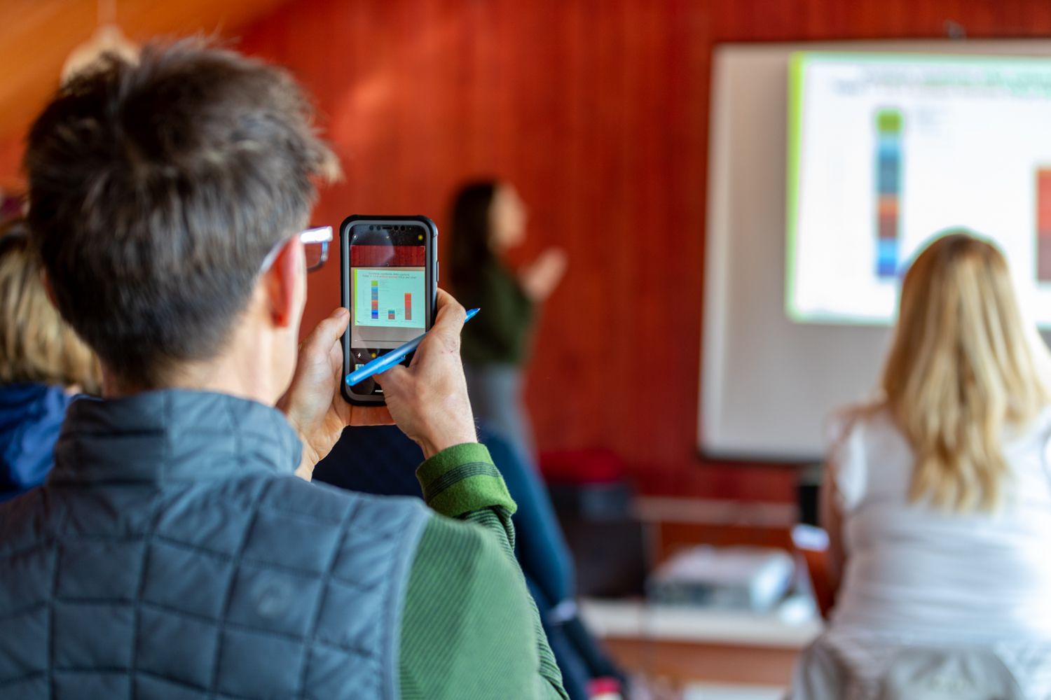 A man taking a picture of a presentation on his phone