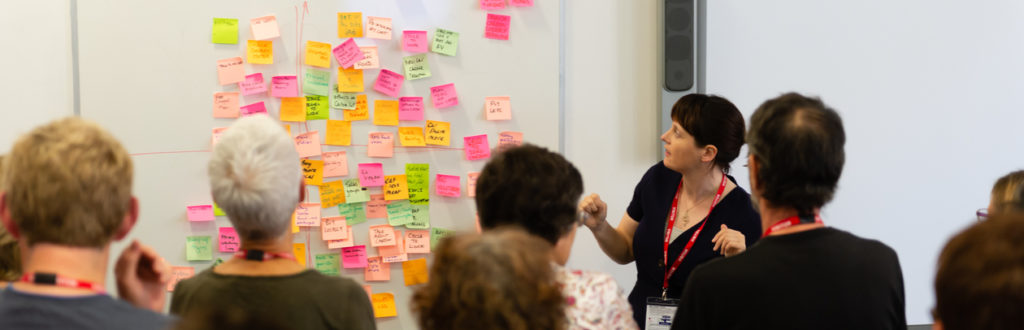 A woman leading a carbon literacy course at a whiteboard