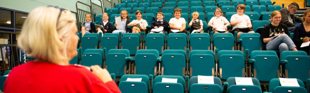 A woman standing in front of a seated row of school pupils
